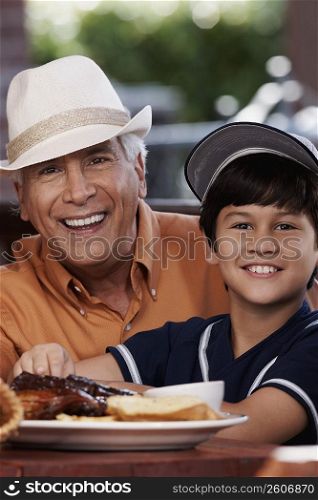 Portrait of a senior man and his grandson sitting in a restaurant and smiling