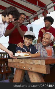 Portrait of a senior man celebrating his grandson&acute;s birthday in a restaurant