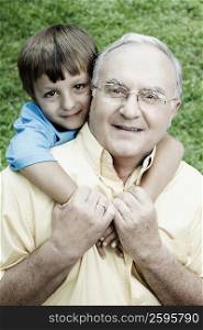 Portrait of a senior man giving a piggyback to his grandson and smiling