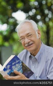 Portrait of a senior man holding a book and smiling