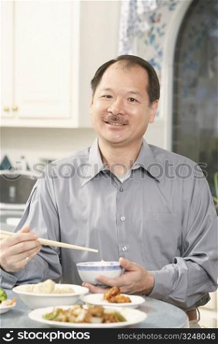 Portrait of a senior man holding a bowl with a pair of chopsticks
