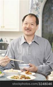 Portrait of a senior man holding a bowl with a pair of chopsticks