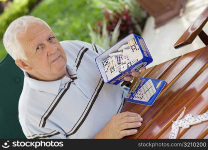 Portrait of a senior man holding a box of dominos