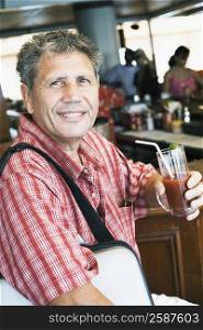 Portrait of a senior man holding a glass of juice and smiling
