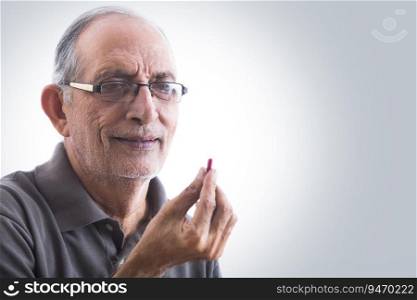 Portrait of a senior man holding a pill in hand.  Health and fitness  