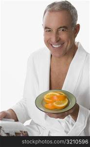 Portrait of a senior man holding a plate of orange and smiling
