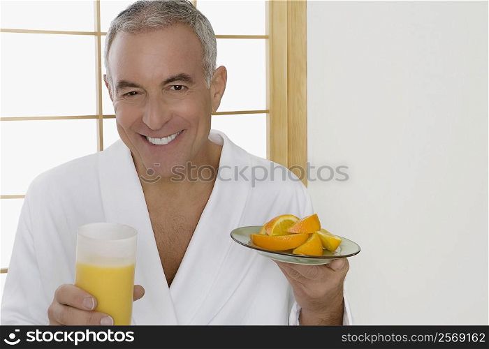 Portrait of a senior man holding a plate of oranges and a glass of orange juice