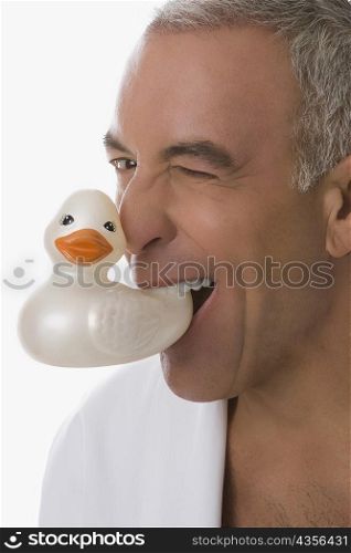 Portrait of a senior man holding a toy duck in his mouth