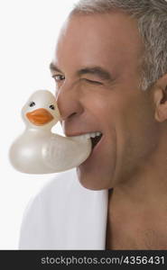 Portrait of a senior man holding a toy duck in his mouth