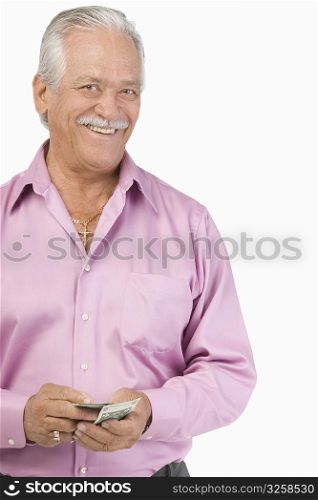 Portrait of a senior man holding paper currencies and smiling