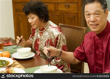 Portrait of a senior man sitting at a dining table with a mature woman beside him