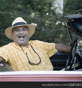Portrait of a senior man sitting in a convertible car and laughing