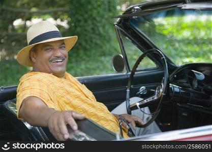Portrait of a senior man sitting in a convertible car and smiling