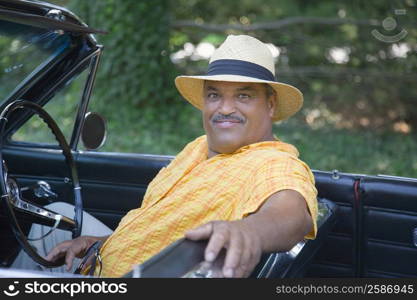 Portrait of a senior man sitting in a convertible car and smiling