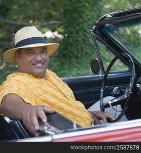 Portrait of a senior man sitting in a convertible car and smiling