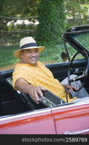 Portrait of a senior man sitting in a convertible car and smiling