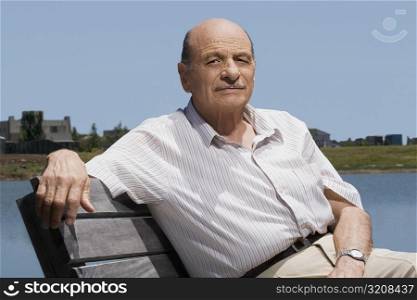 Portrait of a senior man sitting on a bench at the lakeside