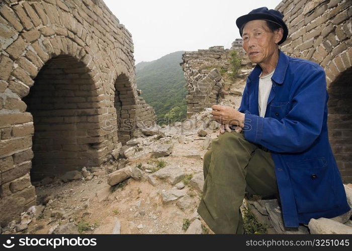 Portrait of a senior man sitting on a wall, Great Wall Of China, Beijing, China