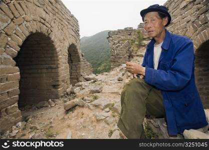 Portrait of a senior man sitting on a wall, Great Wall Of China, Beijing, China