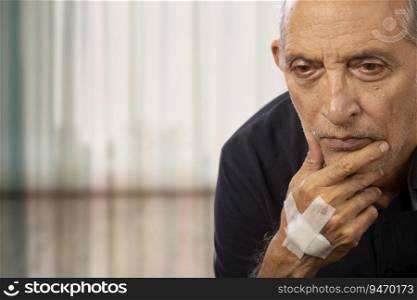 Portrait of a senior man sitting with a bandage on his hand.  Health and fitness  