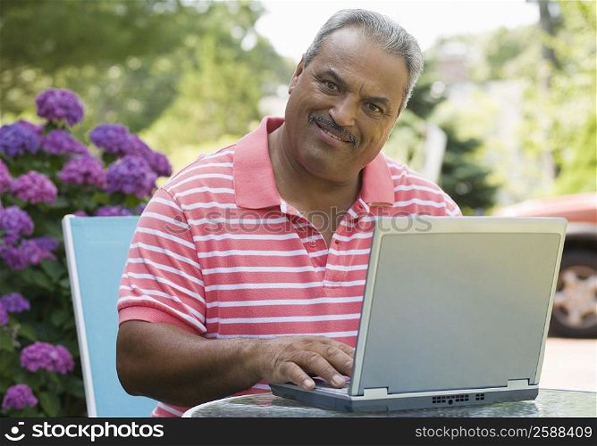 Portrait of a senior man using a laptop and smiling