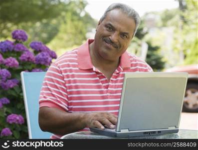 Portrait of a senior man using a laptop and smiling