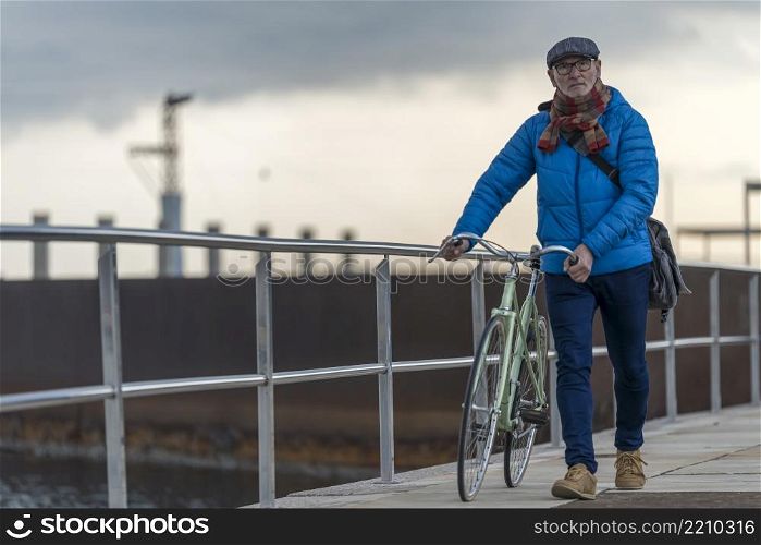 Portrait of a senior man walking with his bicycle next to the sea
