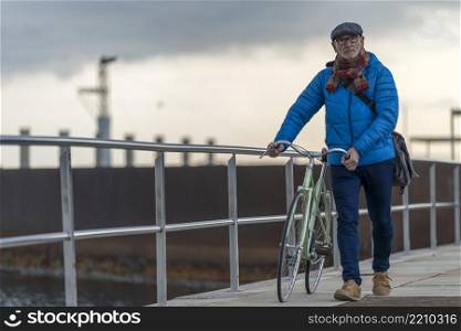 Portrait of a senior man walking with his bicycle next to the sea