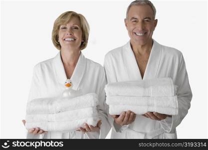 Portrait of a senior man with a mature woman standing together and holding folded towels