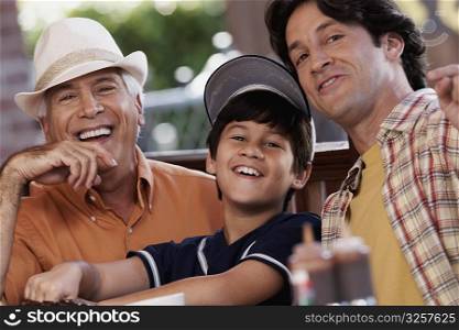 Portrait of a senior man with his son and grandson sitting in a restaurant and smiling