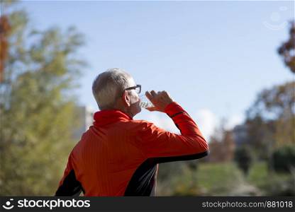 Portrait of a senior runner drinking water after jogging