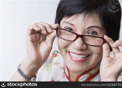 Portrait of a senior woman adjusting her eyeglasses and smiling