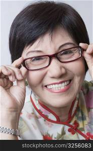 Portrait of a senior woman adjusting her eyeglasses and smiling