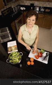 Portrait of a senior woman cutting vegetables on a cutting board in the kitchen