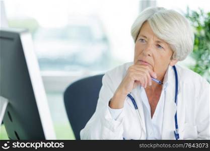portrait of a senior woman doctor looking at screen