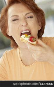 Portrait of a senior woman eating a fruit tart