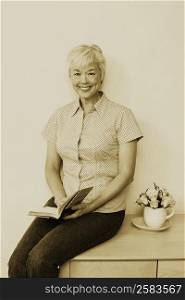 Portrait of a senior woman holding a book and smiling