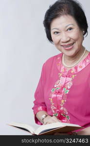 Portrait of a senior woman holding a book and smiling