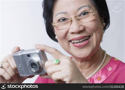 Portrait of a senior woman holding a digital camera and smiling