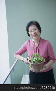 Portrait of a senior woman holding a potted plant and smiling