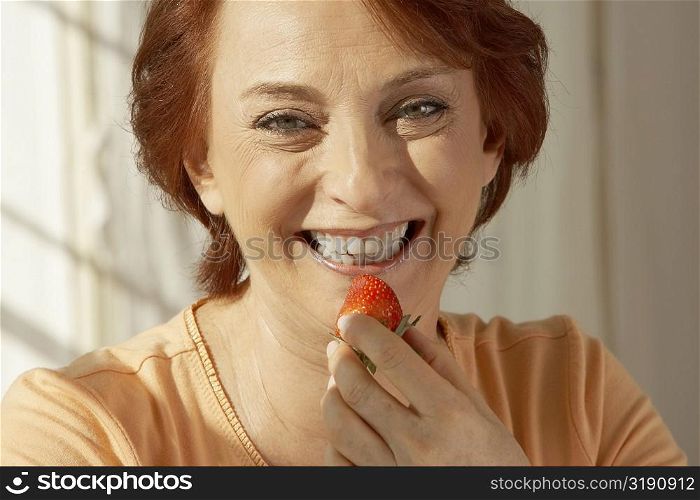 Portrait of a senior woman holding a strawberry