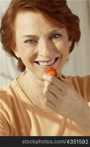 Portrait of a senior woman holding a strawberry