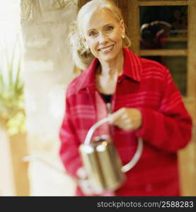 Portrait of a senior woman holding a watering can and smiling