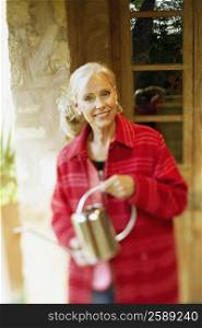 Portrait of a senior woman holding a watering can and smiling