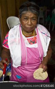 Portrait of a senior woman holding tortilla and cooking, Cuetzalan, Puebla State, Mexico