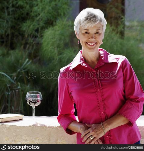 Portrait of a senior woman leaning against a wall on a terrace