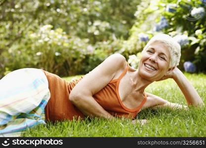 Portrait of a senior woman lying on grass and smiling