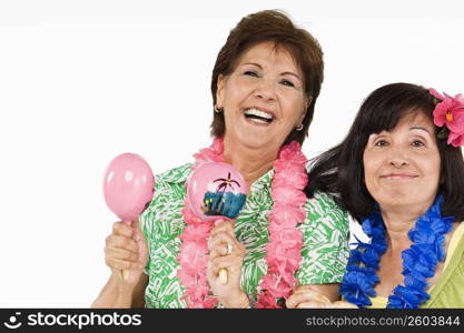 Portrait of a senior woman playing maracas and her friend grinning beside her