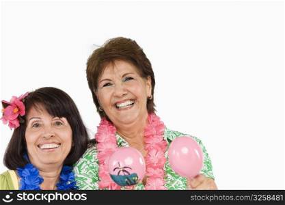 Portrait of a senior woman playing maracas and her friend smiling beside her