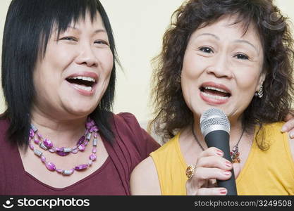 Portrait of a senior woman singing with a mature woman in front of a microphone